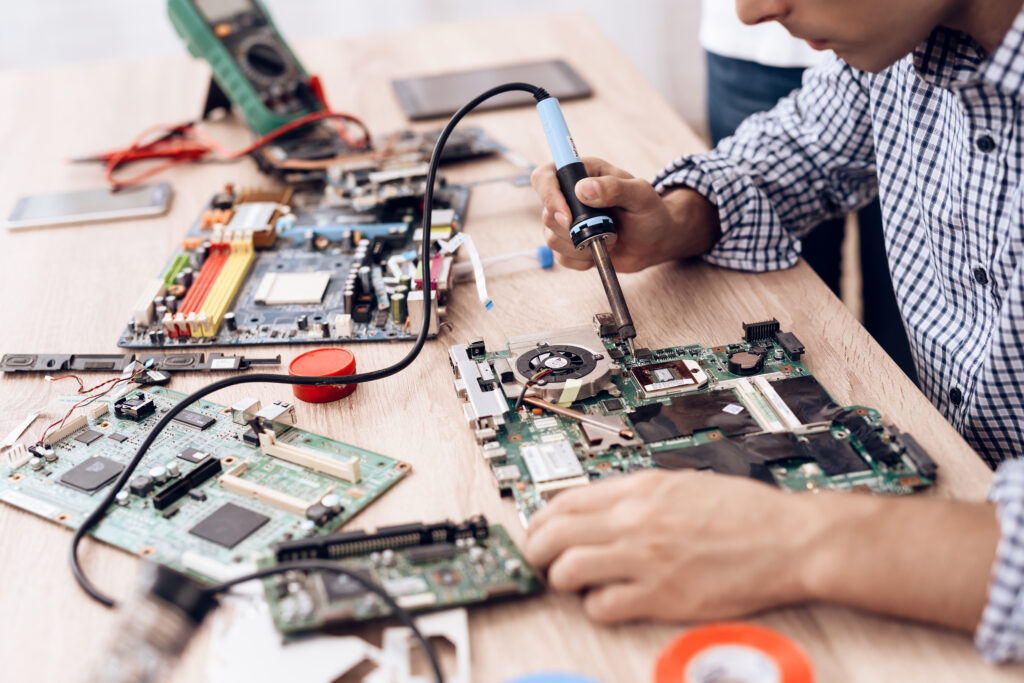 The man works as a radio technician. A man is repairing a printed circuit board.